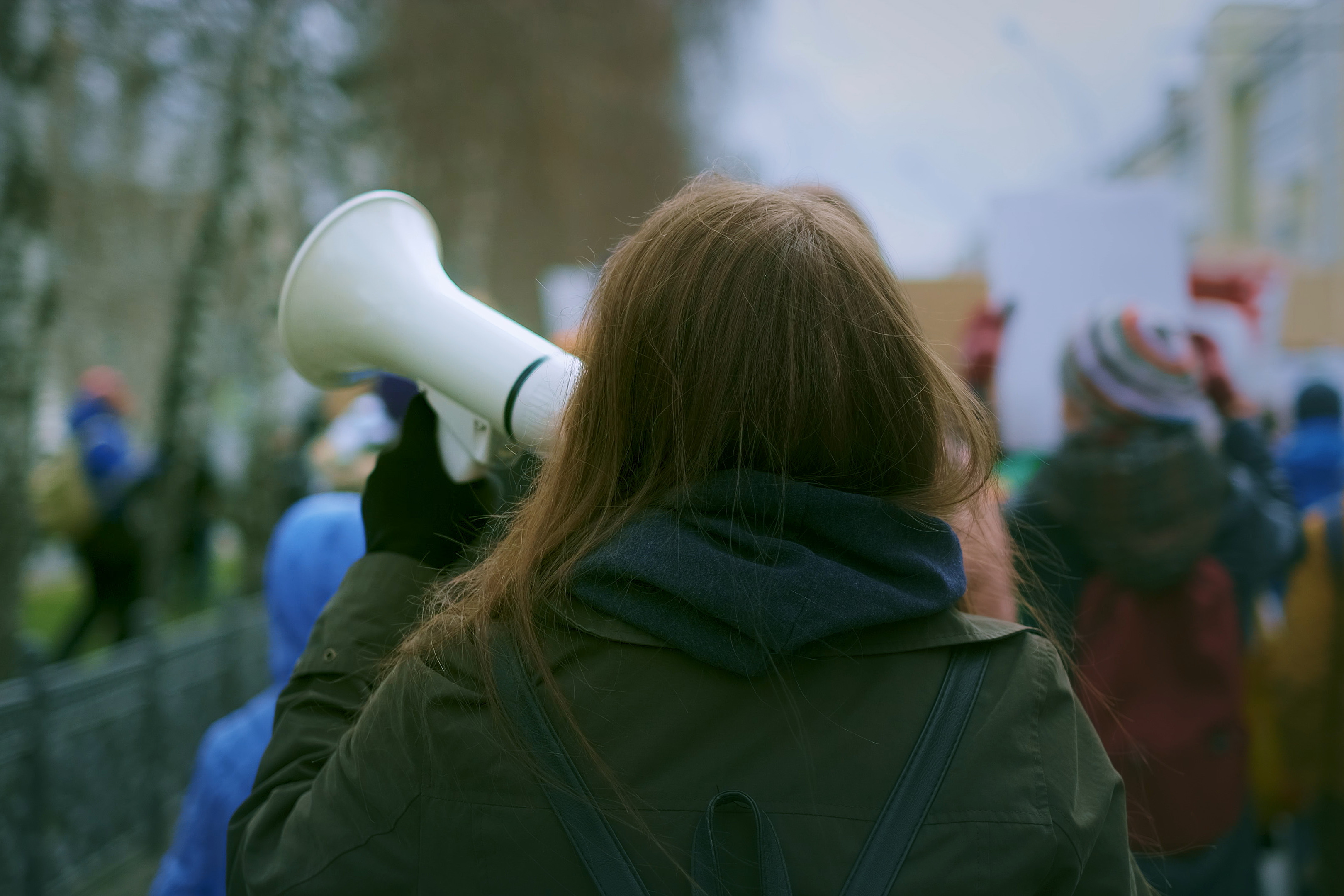 View from behind of a person holding a megaphone at a protest rally.