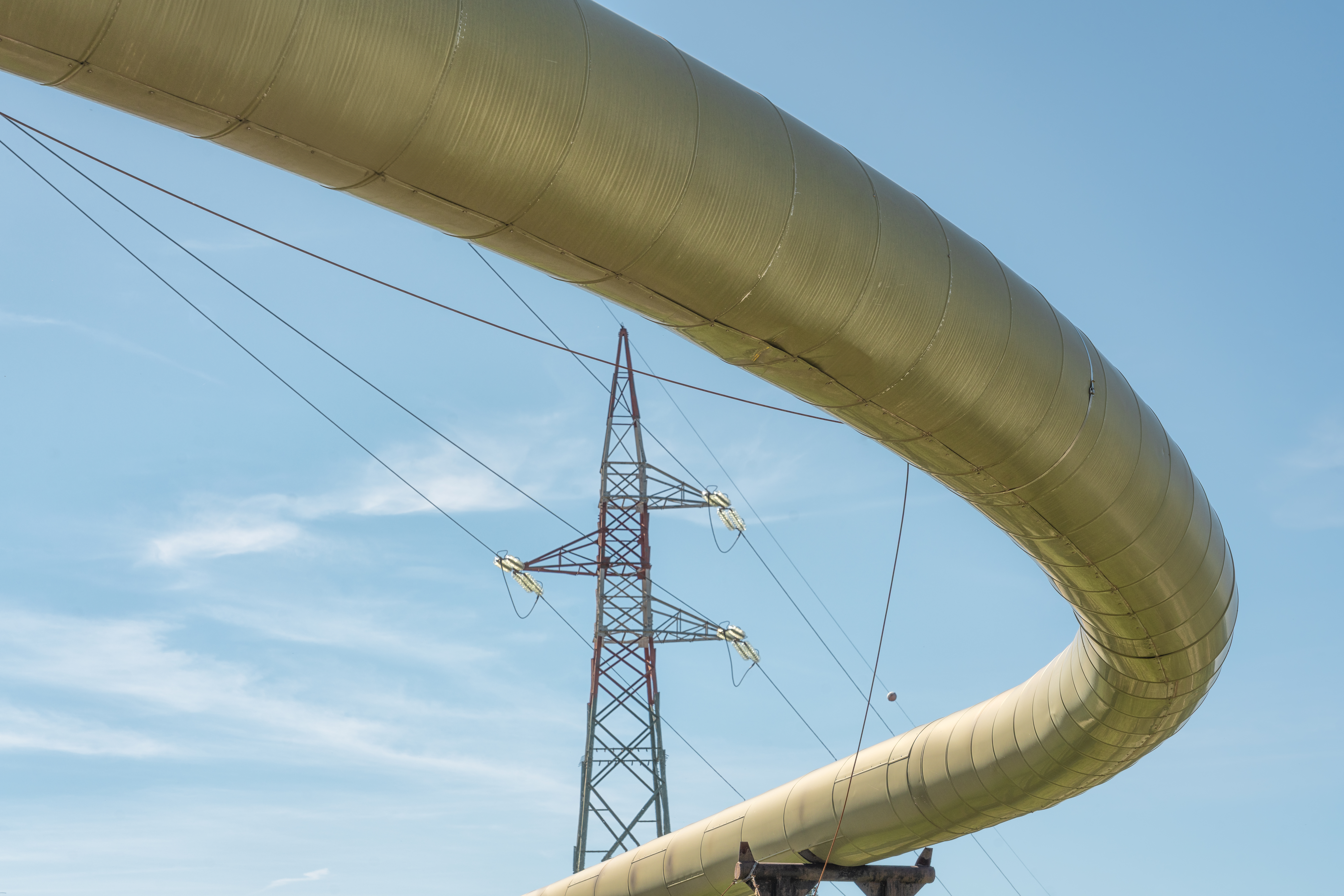 Pipeline representing geothermal energy with a high voltage power line in the background.
