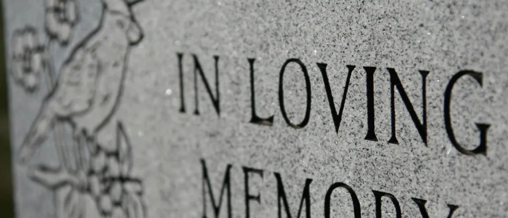 Grave marker inscribed with 'In Loving Memory' - iStock - melissarobison