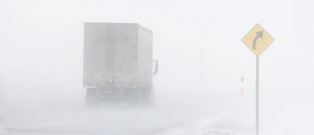 PROMO HIRES Weather - Truck Road Sign Snow Blizzard - lloydmp - iStock-145131807 Semi truck on a snow-covered road