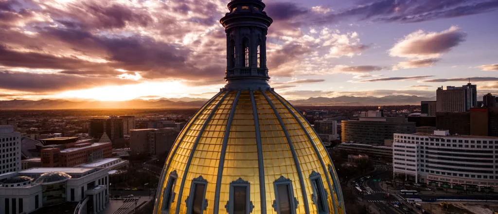 Aerial view of the Colorado capitol building dome with clouds at sunset.