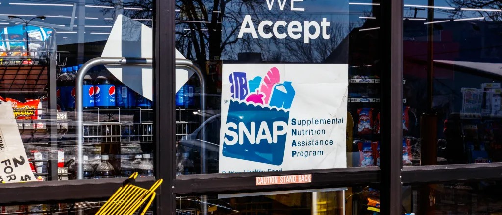 Sign in the window of a store stating that Supplemental Nutrition Assistance Program (SNAP) benefits are accepted.