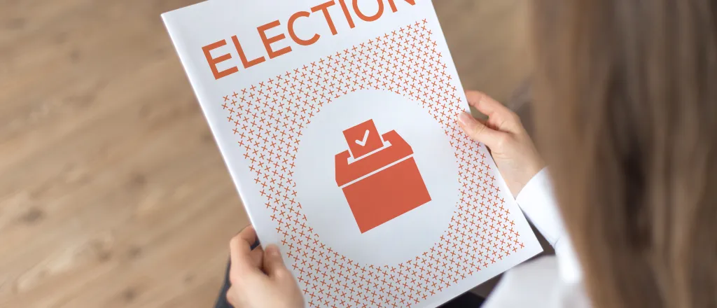 PROMO HIRES Politics - Election Guide Booklet Vote Ballot - iStock - relif Person holding a booklet titled "Election"