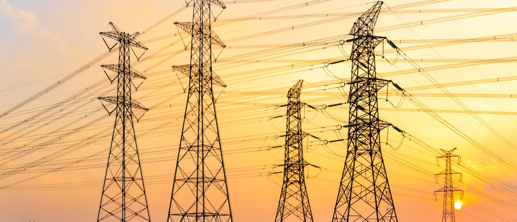High voltage transmission towers stretching into the distance at sunrise/sunset
