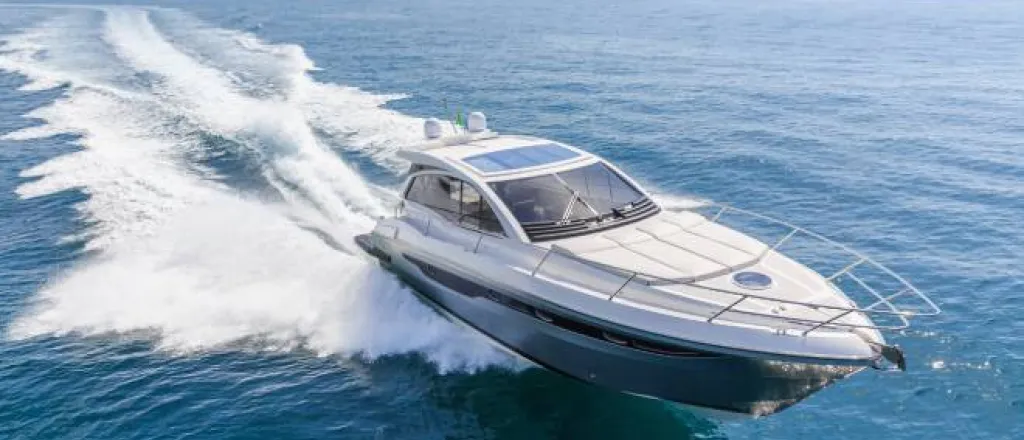 A blue and white luxury motorboat racing through a large body of water and leaving a wake behind it. A blue and white luxury motorboat racing through a large body of water and leaving a wake behind it.