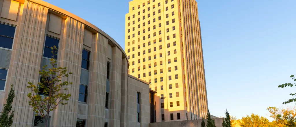 View of the North Dakota Capitol Building from an angle. The main tower is on the right side of the image.