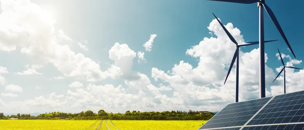 Solar panels and wind turbines near a vehicle path crossing a field