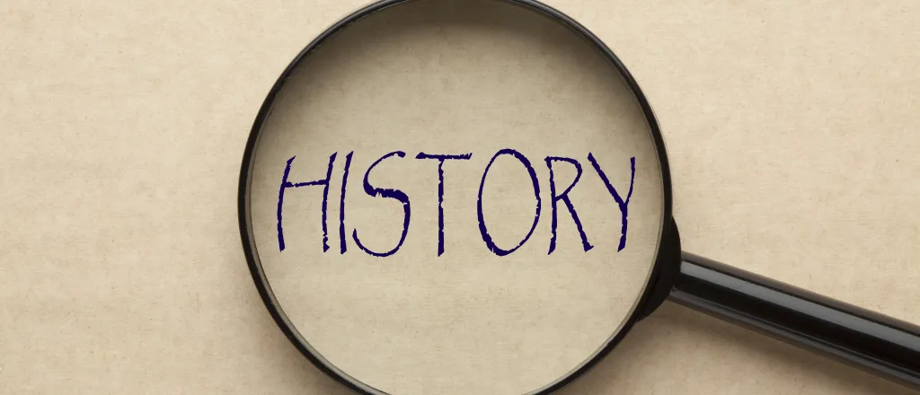 Overhead view of a magnifying glass over the word "history."