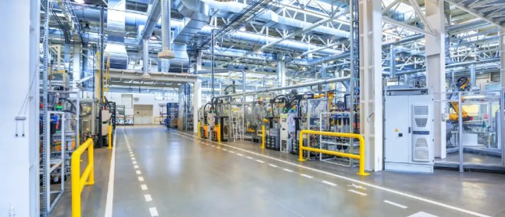 A clean factory floor with clear lanes designated for employees. Machines and industrial equipment fill the space.