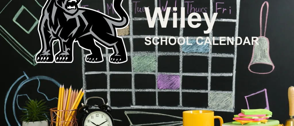The Wiley School Panthers mascot, beside a chalkboard drawn with a weekly calendar grid above a desk of pencils, a clock and notebooks. The board reads “Wiley School Calendar”.