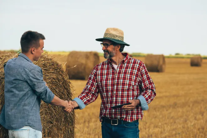 PICT Two people standing near a large hay bale - FamilyFeatures