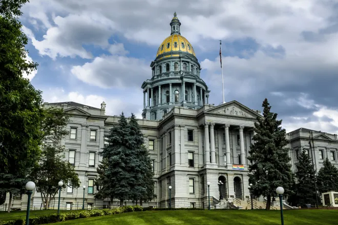 Colorado State Capitol Building fronted by green trees under a cloudy sky