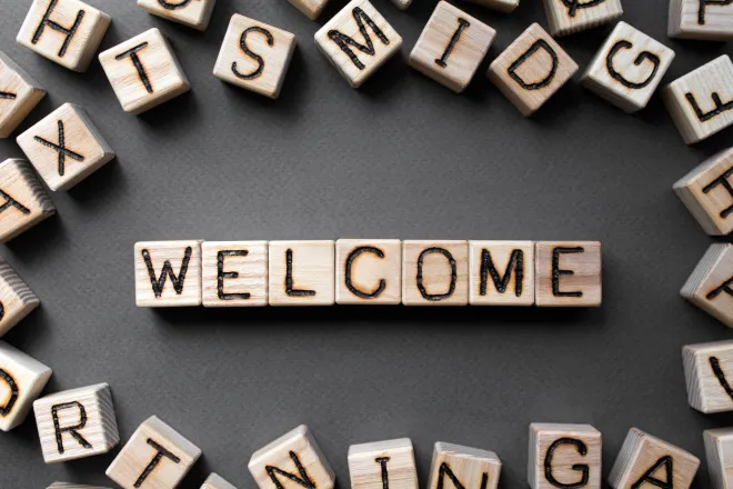 Assorted wooden blocks with letters on the side, surrounding wooden blocks spelling the word "welcome"