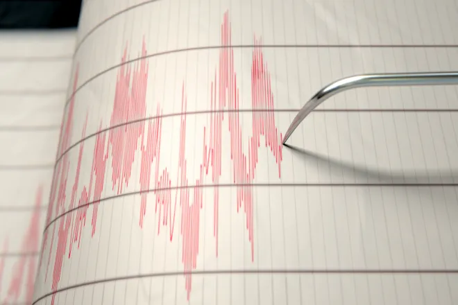 Earthquake seismograph paper with a stylus pen recording large activity variations.