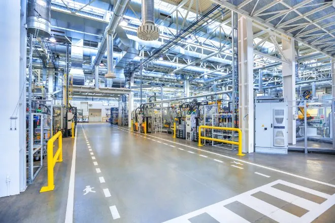 A clean factory floor with clear lanes designated for employees. Machines and industrial equipment fill the space.