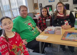 2023 Crazy Sweater day at Plainview School in Kiowa County, Colorado. Adults and children seated at a table wearing holiday sweaters.