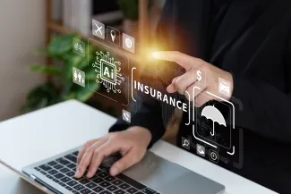 Hands of a business professional near computer and holographic symbols - Poca Wander Stock - iStock-1470986827