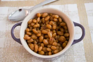 Pot of baked beans on a table with a spoon.