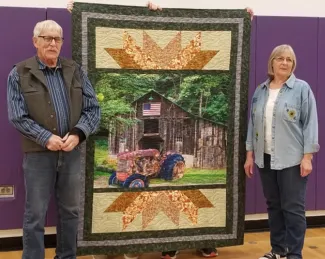 Roger and Betsy Evans. Courtesy Rayetta Addy. Man and woman standing on either side of a quilt.