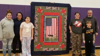 Ryan Weber and family. Courtesy Rayetta Addy People standing with a quilt.