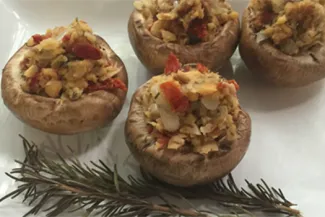 Herb-Stuffed Mushrooms. Plat of herb-stuffed mushrooms with a sprig of rosemary.