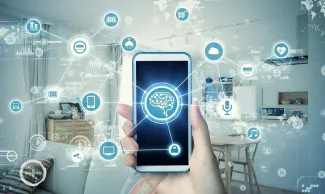 Hand holding a cell phone in front of a home scene surrounded by icons of various technologies