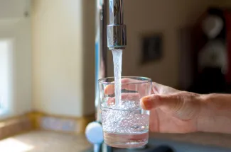 PROMO HIRES Water Faucet Tap Drinking Glass Drought - mheim3011 - iStock-544332118 Hand filling a glass with water from a faucet.