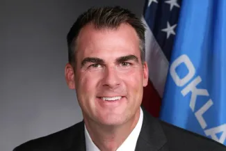 Politician - Oklahoma Governor Kevin Stitt Oklahoma Governor Kevin Stitt posing in front of the Oklahoma state flag
