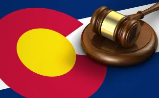 PROMO HIRES Legal - Court Law Colorado Flag Gavel Justice - iStock - NiroDesign Gavel resting on a strike plate on top of a Colorado state flag.