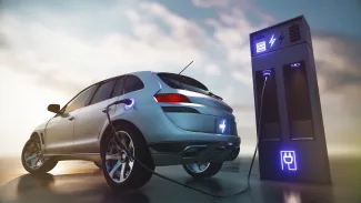 PROMO HIRES Transportation - Electric Vehicle Car EV Charging - UniqueMotionGraphics - iStock-1477067152 Electric car at a charging station with clouds in the background