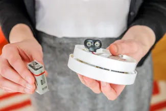 PROMO HIRES Safety - Smoke Carbon Monoxide Alarm Battery - AdrianHancu - iStock-640029484 Person holding a smoke alarm or carbon monoxide alarm to change the battery.