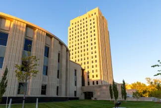 View of the North Dakota Capitol Building from an angle. The main tower is on the right side of the image.