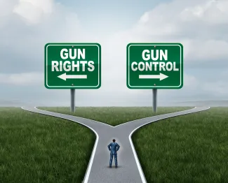 PROMO HIRES Government - Sign Gun Rights Control - iStock - wildpixel Illustration of a person on a road with diverging paths. Two signs are on the horizon. On the left is a sign with an arrow pointing left reading "gun rights." On the right is a sign with an arrow pointing right reading "gun control."