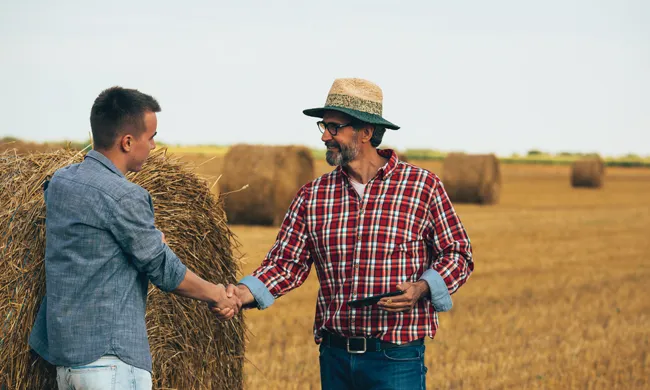 PICT Two people standing near a large hay bale - FamilyFeatures