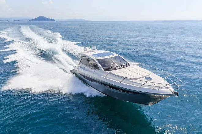 A blue and white luxury motorboat racing through a large body of water and leaving a wake behind it.