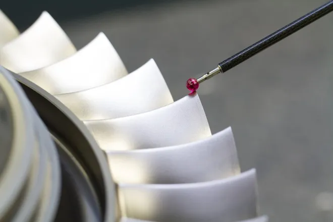 A close-up of a CMM stylus with a ruby tip taking the measurements of a part. The part has many ridges.