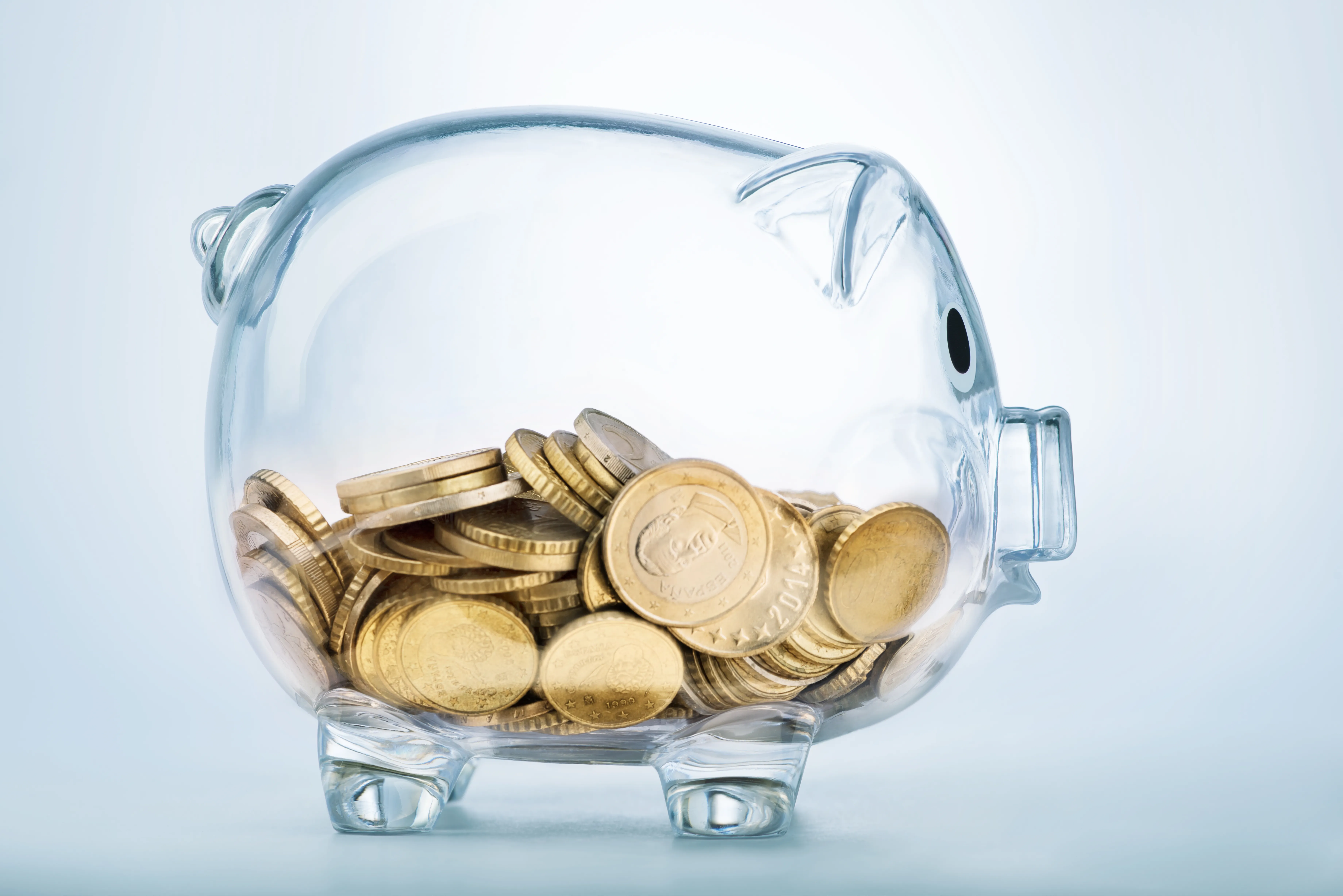 Glass piggy bank half filled with gold coins