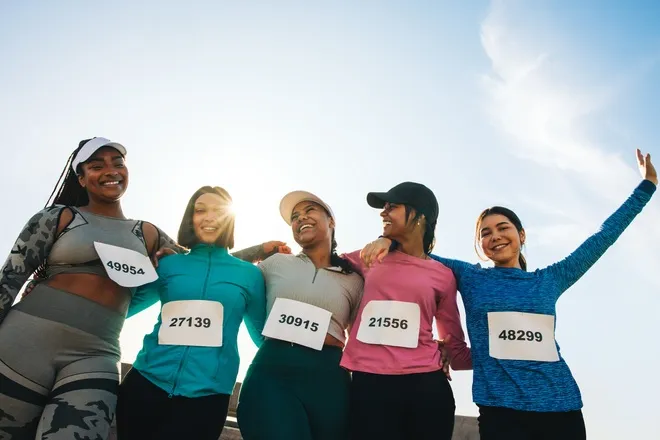 A group of diverse women is celebrating before or after a sporting competition. They're all smiling and laughing.