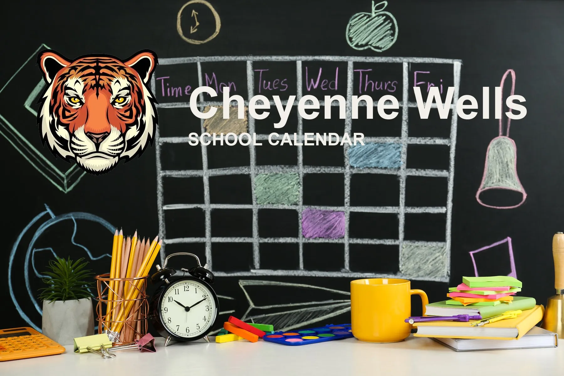 The Cheyenne Wells School Tigers mascot, beside a chalkboard drawn with a weekly calendar grid above a desk of pencils, a clock and notebooks. The board reads “Cheyenne Wells School Calendar”.
