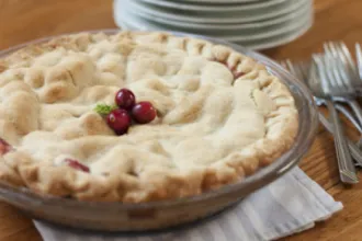 Pie on a plate next to stacks of plates and forks.