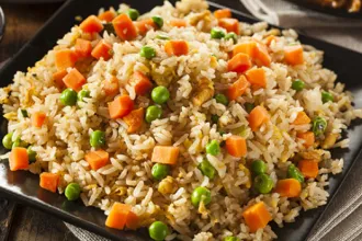Flavorful Fried Rice Square plate of fried rice with peas and carrots