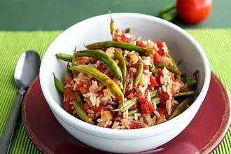 Green bean and rice casserole. Bowl of green bean and rice casserole sitting on a place next to a spoon.