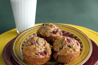 Banana Berry Muffins - USDA Stack of two plates on a placemat with three Banana Berry Muffins next to a glass of milk.