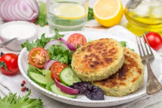 Baked Walleye Patties - USDA Plate with a fork, two walleye patties and an assortment of fresh vegetables, surrounded by fresh vegetables and fruit.