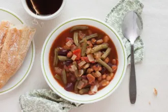 Italian Bean Soup Bowl of Italian Bean Soup on a cloth. Near by are a spoon, cup of hot tea, and plate with bread.