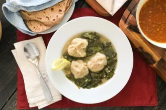 Kibbeh Khamoustah Bowl of Kibbeh Khamoustah next to a spoon and napkins. A nearby cloth holds flat bread.