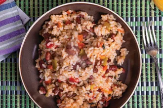 Vegetable and Rice Skillet Meal. Plate containing vegetables and rice on a mat next to a fork and cloth.