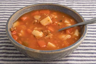 Manhattan Clam Chowder - USDA Bowl of Manhattan clam chowder with a spoon resting inside