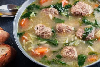 Meatball Soup - USDA Overhead image of a bowl of meatball soup next to a spoon.