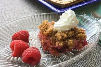 Passover Rhubarb Cobbler - USDA Glass serving dish of Passover rhubarb cobbler with three fresh raspberries.